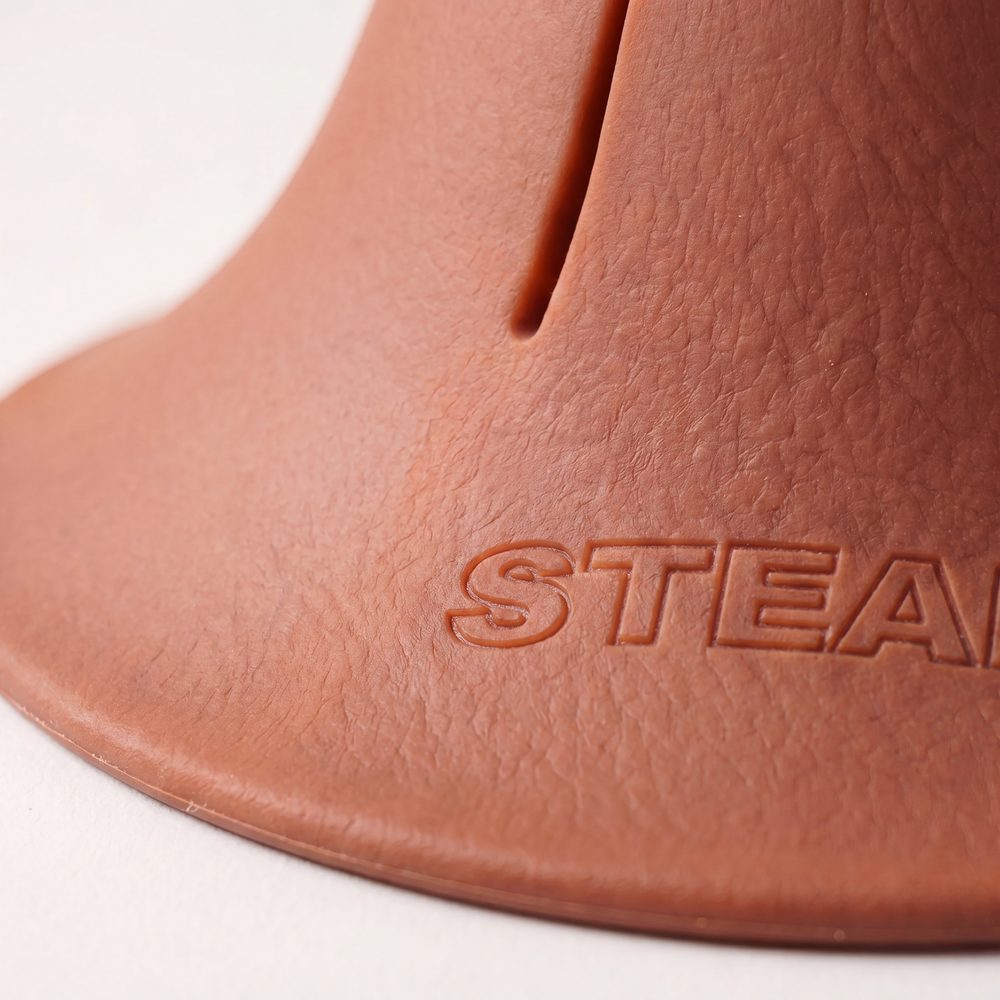 A macro photograph of the flared base of a terracotta Steadi, with the moulded STEADI mark across it.